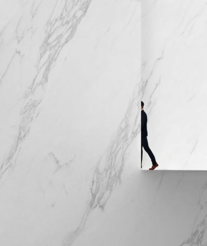 White marble wall with a figure walking through a vertical opening